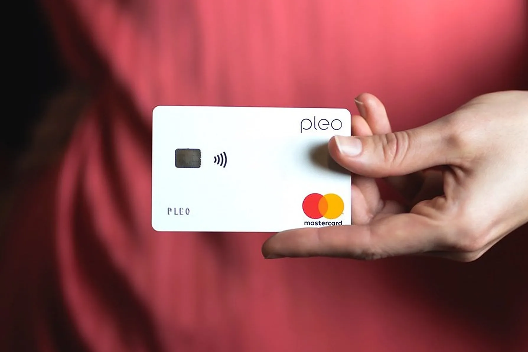 A hand holding a Pleo company card